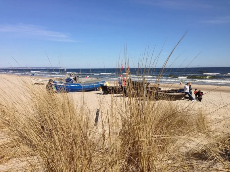 Strandbild in Baabe mit Dünen, alten Holzbooten und Urlaubern